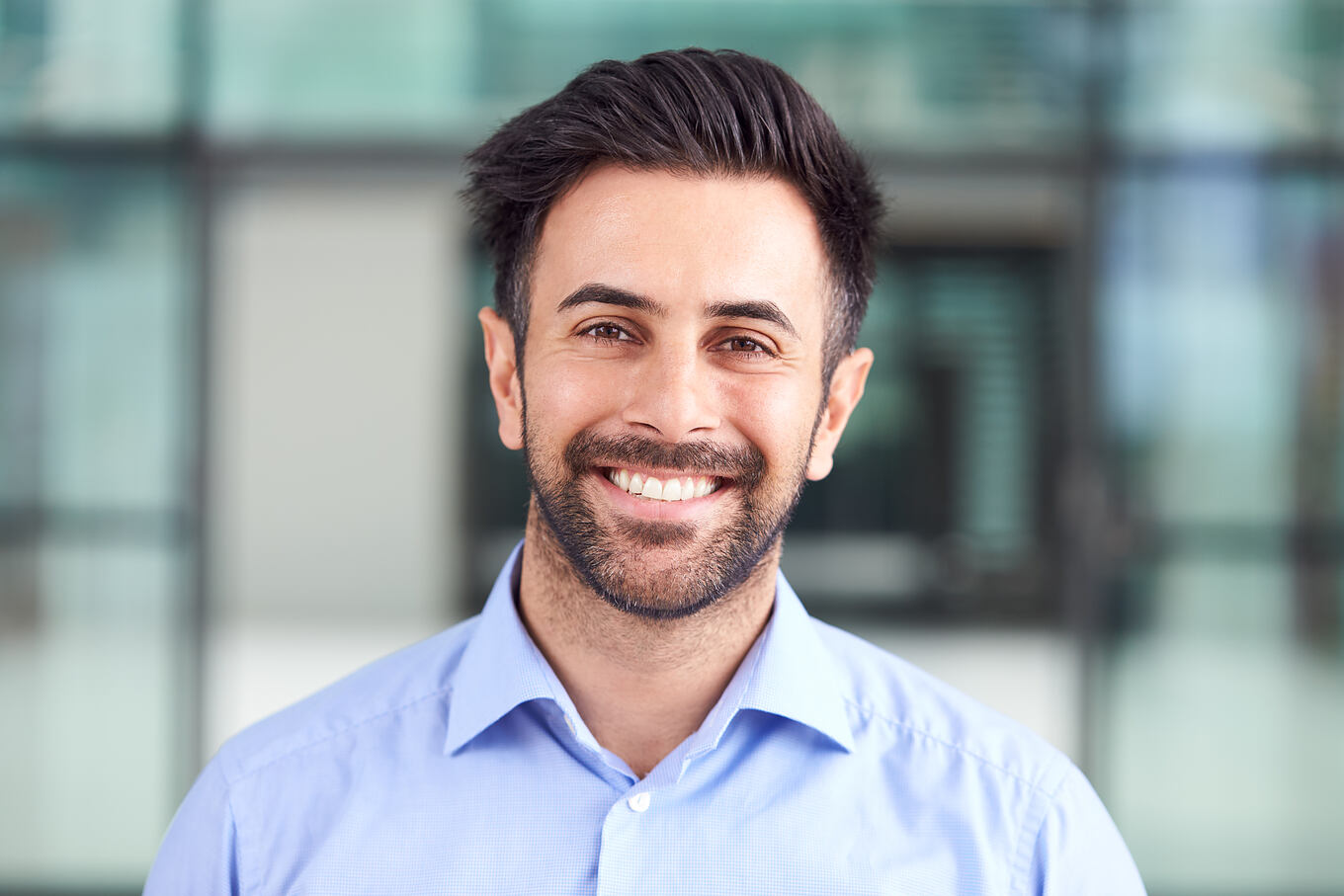Portrait,Of,Smiling,Businessman,Standing,In,Lobby,Of,Busy,Modern
